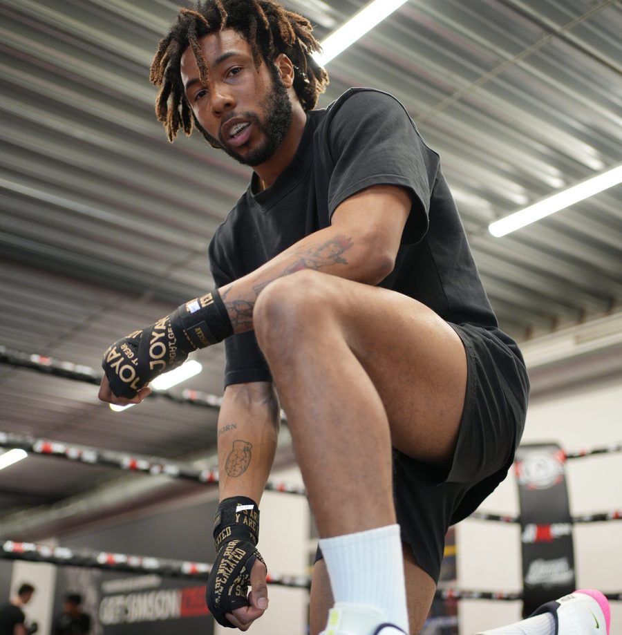 Een sporter met zwarte handwraps zet zijn voet omhoog in de zaal van Simson Gym