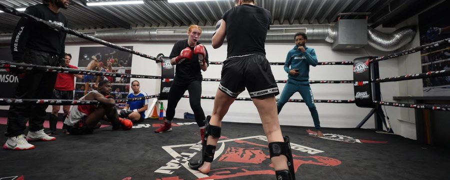 De trainingszaal met ring, trainers en sporters tijdens een les
